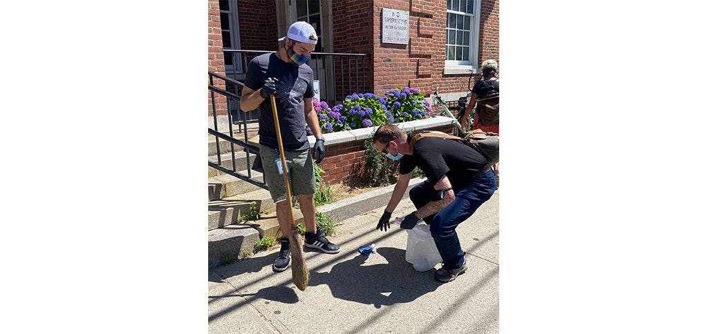 A Curaleaf Provincetown associate helps clean up a sidewalk