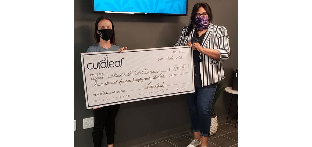 Curaleaf Oxford manager hands a check to the LOCS Collective
